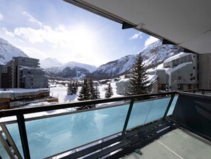 A modern hotel with a glass balcony overlooking a snowy mountain landscape. - Fully renovated studio in La Daille (Val-d'Isère)