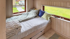 A cozy room with a bed, wooden walls, and a window overlooking a green lawn. - Beautiful home in Gilleleje with WiFi (Gilleleje)