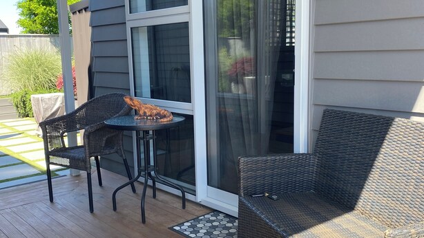 A covered patio with wicker furniture, a table, and a sliding glass door leading to a covered area.
