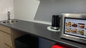 A kitchen with a stainless steel sink, a coffee maker, and a Breville combination cooking appliance displaying various cooking options.