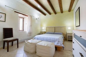 A bedroom with a bed, bedside tables, a chair, and a window. - Casa del Valle – rural oasis with private pool and charm (Betancuria)