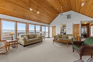 A spacious living room with large windows, a wooden ceiling, and a view of the beach. - 5854 - Erkkila. Relax at Erkkila, your perfect Outer Banks getaway near the beach. (Nags Head)