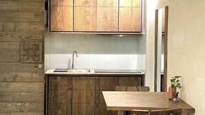 Une cuisine moderne avec des meubles en bois, un évier en acier inoxydable et un coin repas comprenant une table et des chaises en bois.