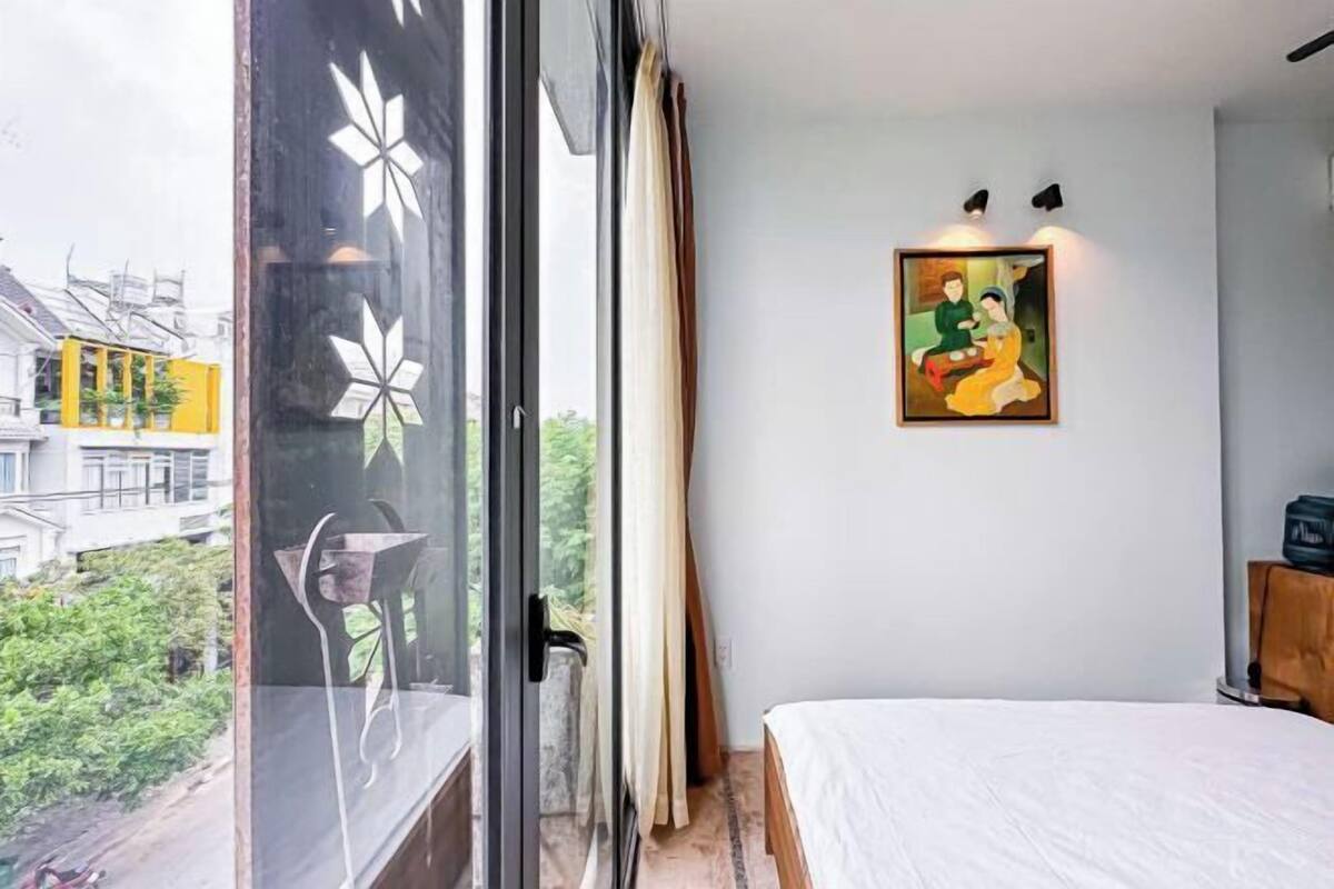 Ein Schlafzimmer mit Bett, einem fensterartigen Ausblick und einem Bild an der Wand.