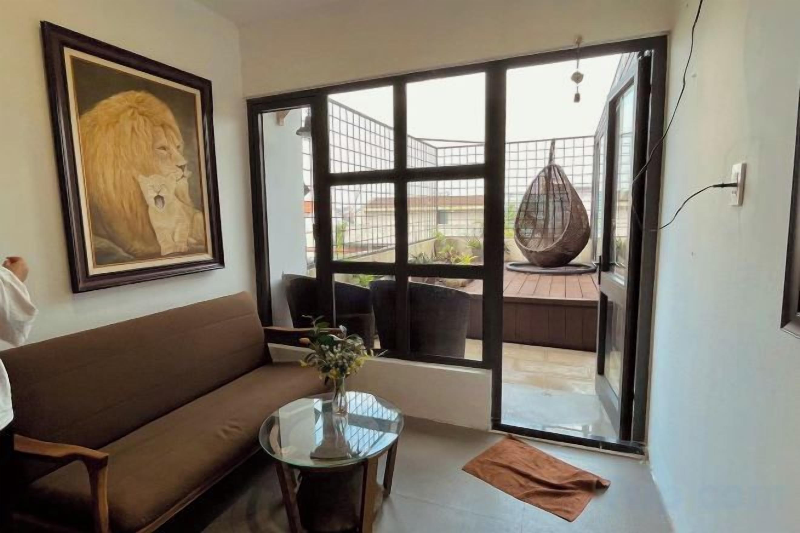 Ein Zimmer mit einer Couch, einem kleinen runden Tisch und einem großen Fenster mit Blick ins Freie.