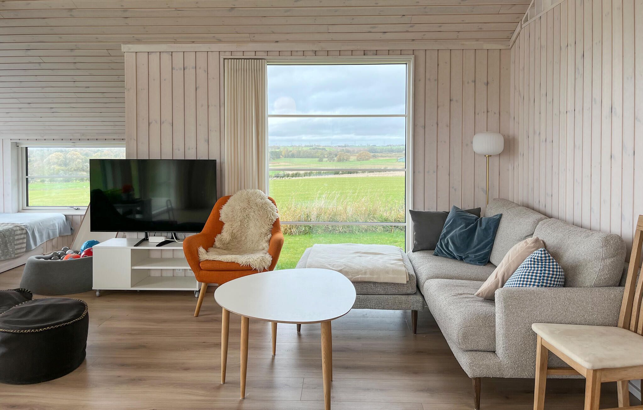 A modern living room with a television, a sofa, a chair, and a table.