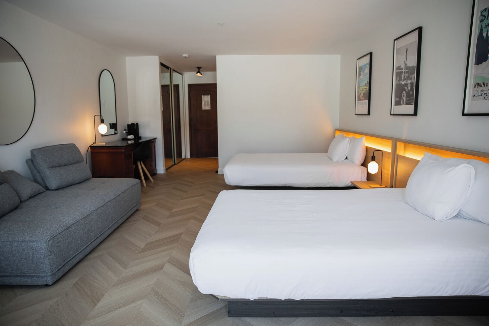 Una habitación de hotel con dos camas, un sofá, un escritorio y un espejo.