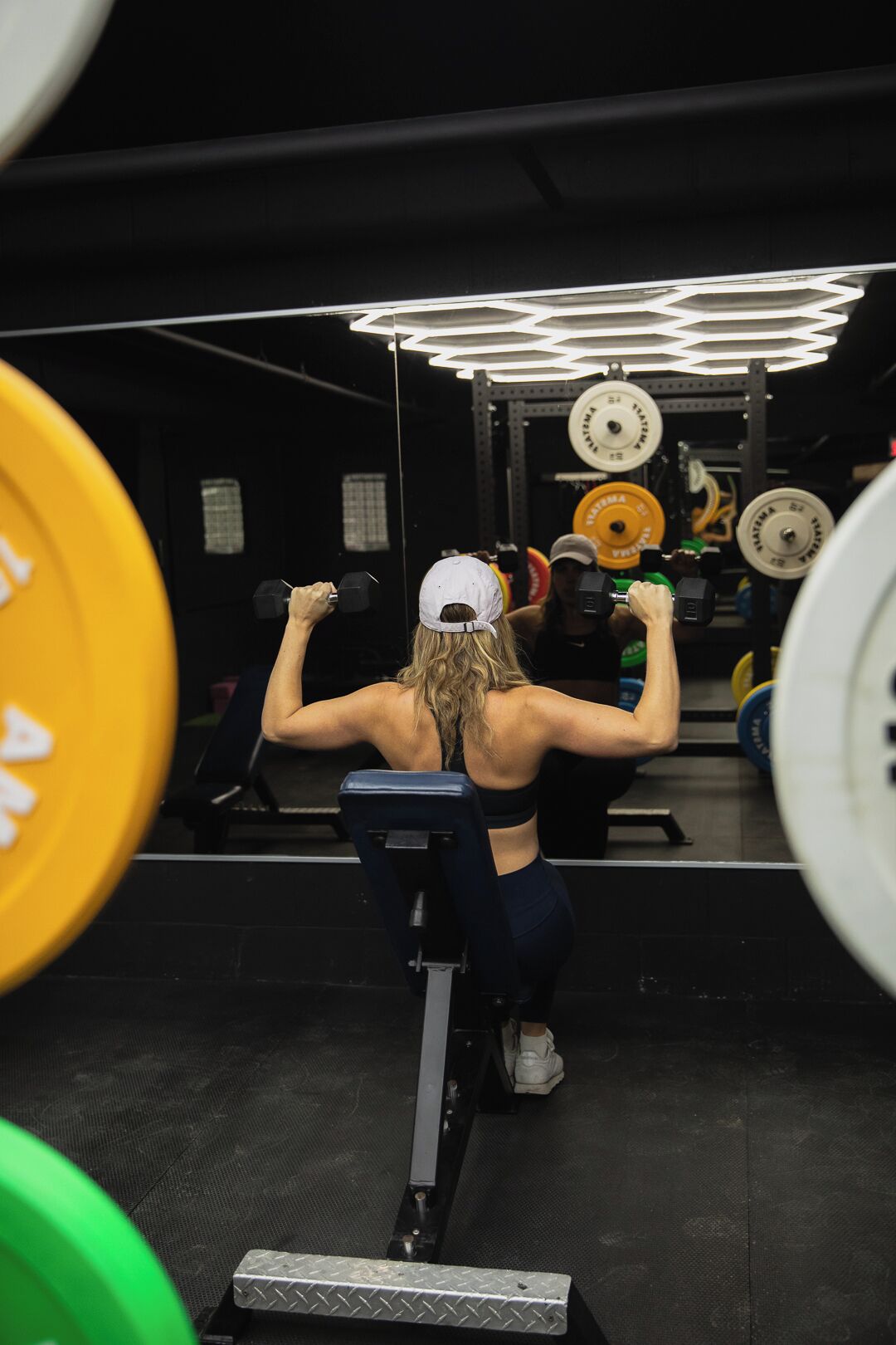 A gym with weightlifting equipment and a person performing a back exercise.