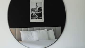 Ein modernes Schlafzimmer mit einem runden Spiegel, der ein Bett und ein gerahmtes Foto widerspiegelt.