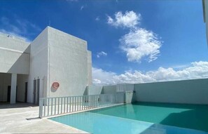 A rooftop pool with a clear blue sky and clouds, surrounded by a white building with a metal railing. - Accommodations with a view of P 17 Beach (Torices)