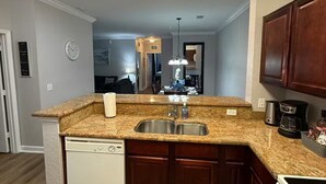 Eine Küche mit Granit-Arbeitsplatten, einer doppelten Spüle und Holzschränken.