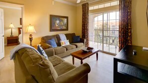 A living room with a sofa, a coffee table, a TV, a painting, and a window with curtains. - Hideaway Gem near Disney & golf. Top floor bonus (Davenport)