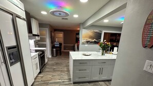 Une cuisine moderne dotée d’un îlot central, d’appareils électroménagers intégrés et d’un parquet en bois disposé en chevrons.