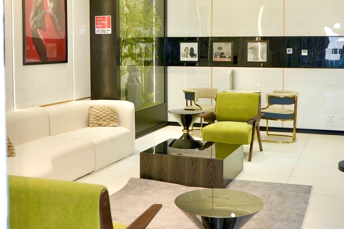 A modern living room with a white sofa, green armchairs, a coffee table, and a glass-top side table.