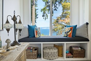 A cozy seating area with a view of the sea, a decorative lamp, and storage baskets. - Kingston Waterfront  View home  with Hot Tub (Kingston)