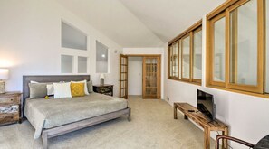 Ein Schlafzimmer mit einem Bett, einem Fernseher, einer hölzernen Bank und einer Tür zu einem anderen Raum.
