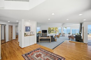 Amplia sala de estar con un ventanal que ofrece vista al mar, una chimenea y un conjunto de asientos acogedor.