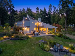 A modern two-story house with a balcony, surrounded by a well-maintained garden and tall trees. - Kingston Waterfront  View home  with Hot Tub (Kingston)