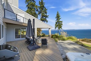 Una terraza con mobiliario exterior, un jacuzzi y vista al mar.