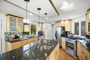 A modern kitchen with granite countertops, stainless steel appliances, and wooden cabinets.