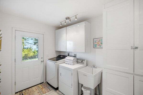 A compact, white-walled laundry room with a washing machine, a dryer, and a sink.