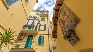A narrow street with yellow buildings, balconies with green shutters, and a mural on the right wall. - VeronaLodge Bilo
Hospitality and Comfort in the Heart of Verona (Verona)