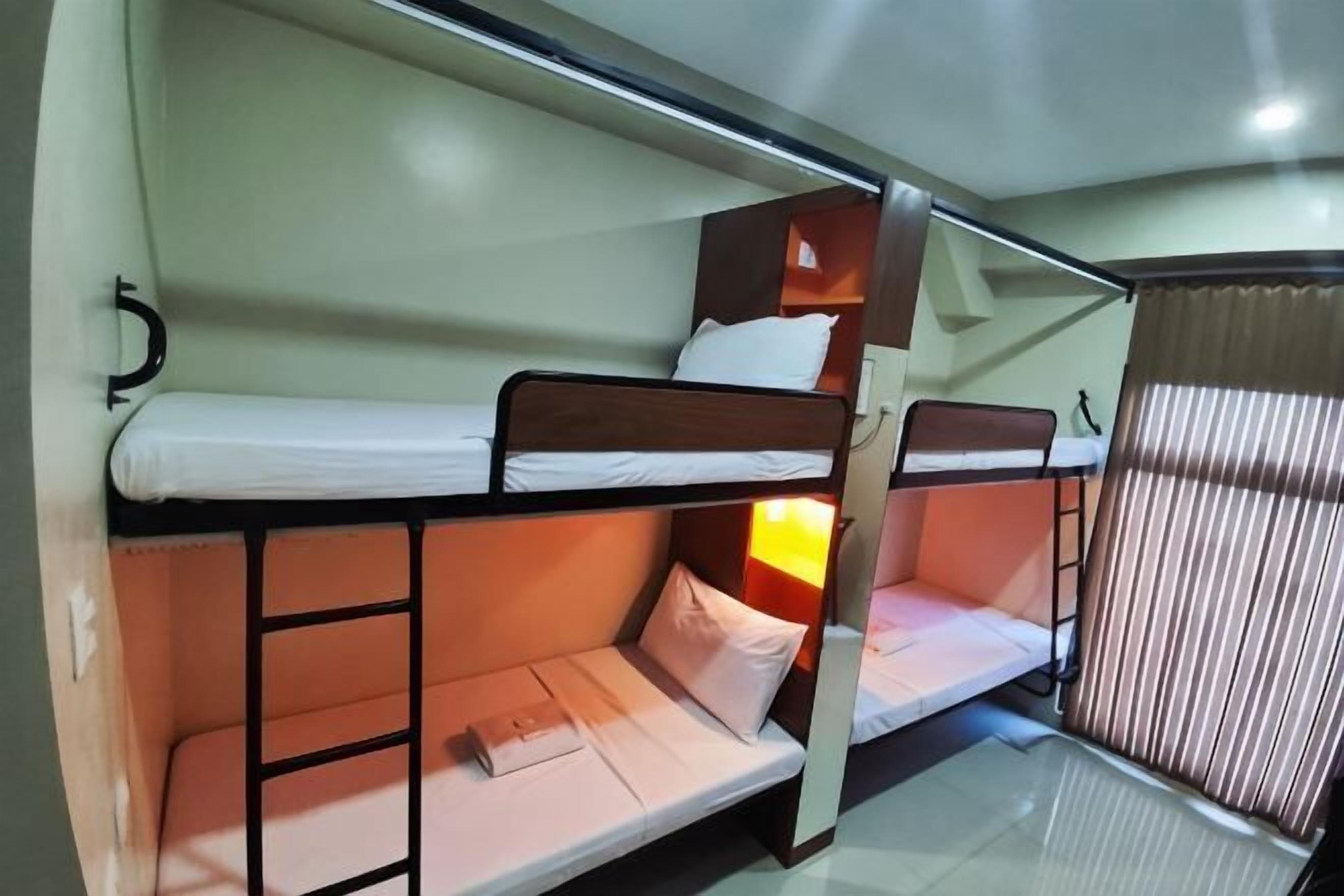 Une chambre avec un lit superposé, une échelle, une petite table et une fenêtre avec des rideaux.