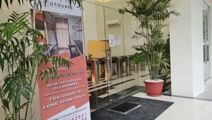 A hotel entrance with a glass door, a potted plant, and a signboard. - G Square Residences (Manila)
