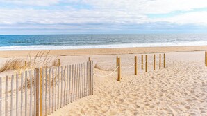 Een zandstrand met een houten omheining en touwbalk.