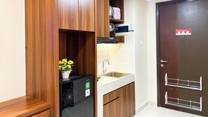 Eine kleine Küche mit Holzausstattung, einem Einbaukühlschrank, einer Spüle und einer Tür mit Sicherheitsschließung.