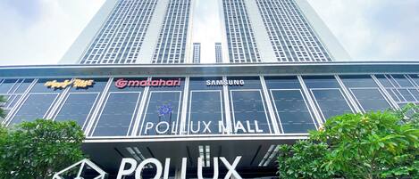 Ein modernes Gebäude mit großen Glasfenstern und Beschilderung für 'Pollux Mall' und 'Samsung'.