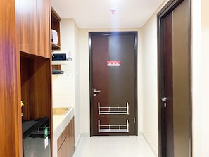 Un pasillo con un armario de madera, un microondas y una puerta con cerradura de seguridad.