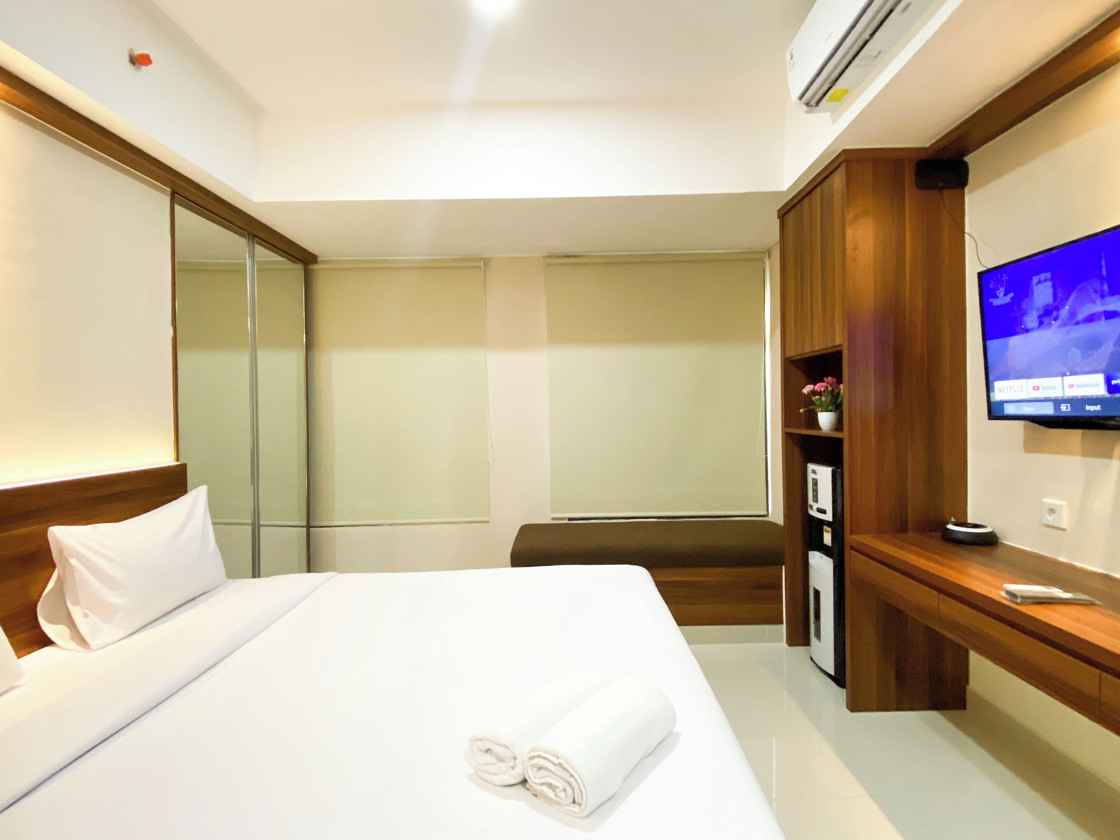 Une chambre d’hôtel avec un grand lit, un téléviseur fixé au mur, une armoire en bois et un miroir.