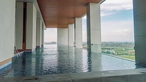 A modern infinity pool with a wooden ceiling and glass railings, offering a view of the cityscape. - Modern And Comfort 1Br At The Smith Alam Sutera Apartment (Tangerang)