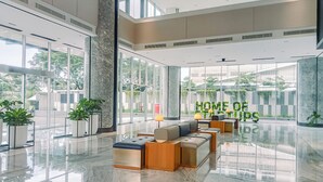 A spacious lobby with a high ceiling, large windows, and a seating area with modern furniture. - Modern And Comfort 1Br At The Smith Alam Sutera Apartment (Tangerang)