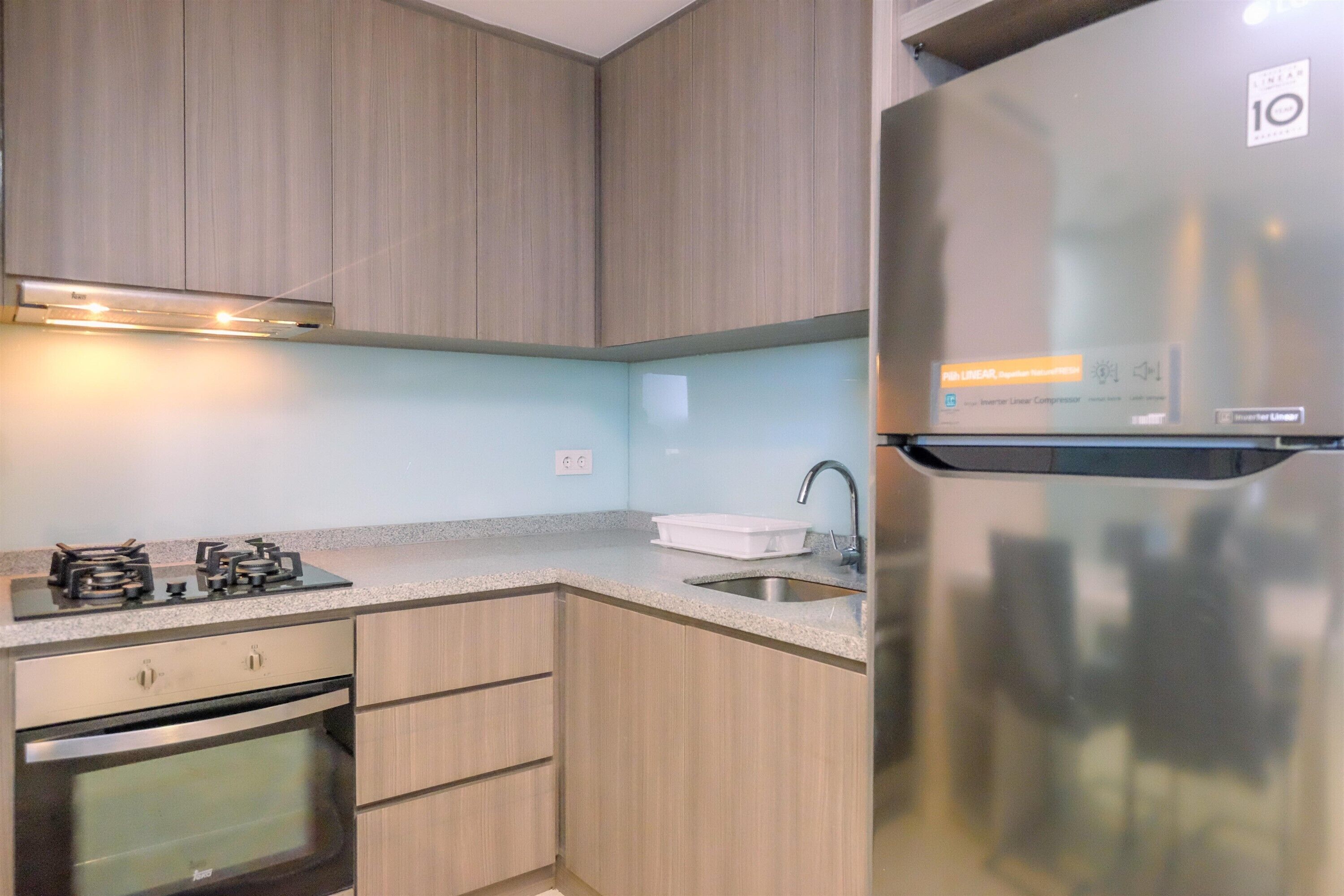 A modern kitchen with wooden cabinets, a stainless steel refrigerator, a built-in oven, and a gas stove.