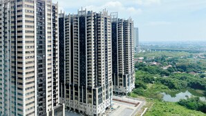 A high-rise residential building with multiple floors, large windows, and a view of a river and greenery in the background. - Homey And Good Choice 2Br At Meikarta Apartment (Cikarang)