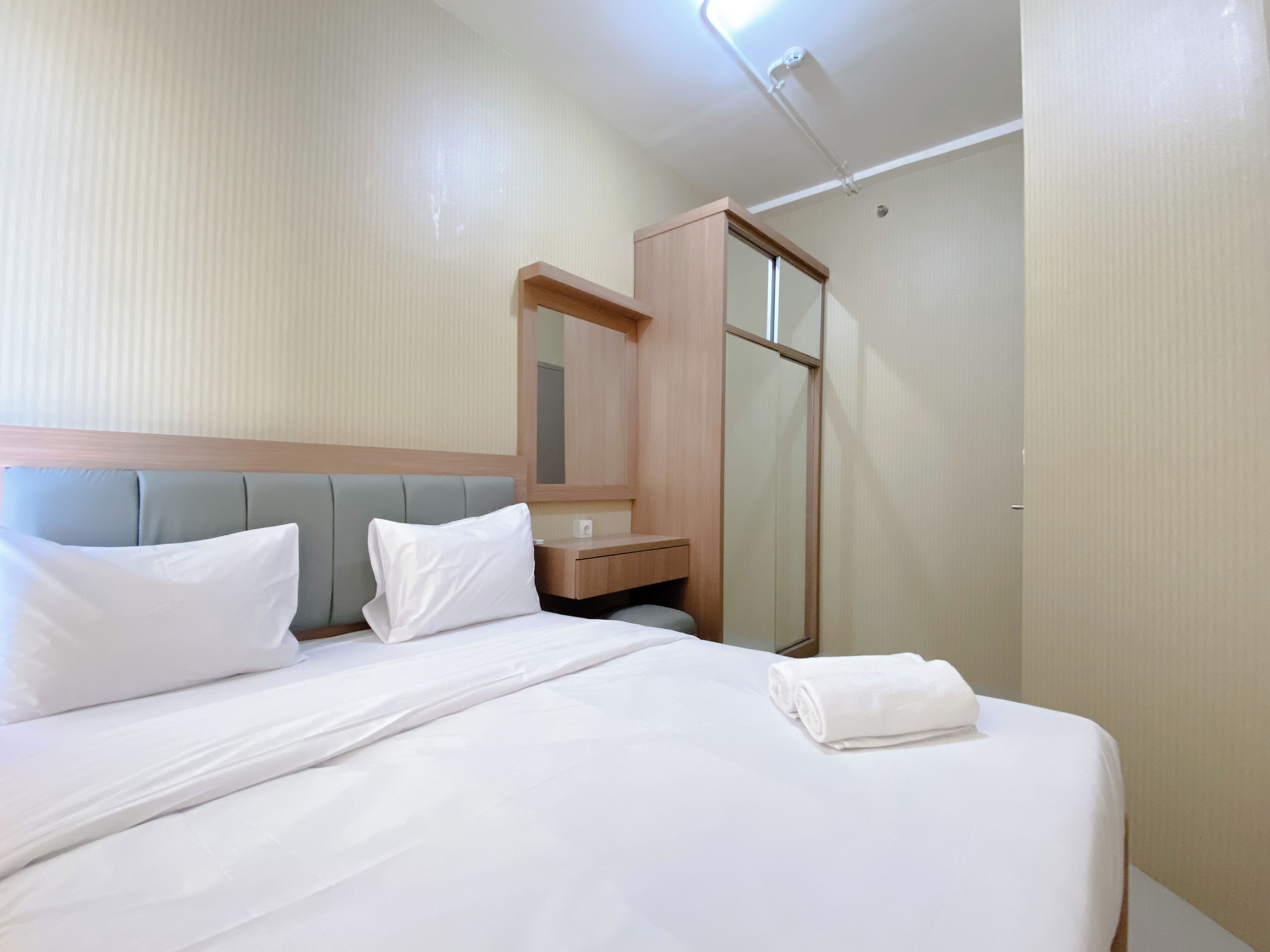 Una habitación de hotel con una cama, una mesita de noche, un espejo y un armario.