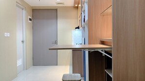 A modern hallway with a wooden bench, a door, and a shelf unit. - Minimalist And Enjoy Living 1Br Vasanta Innopark Apartment (Cikarang)