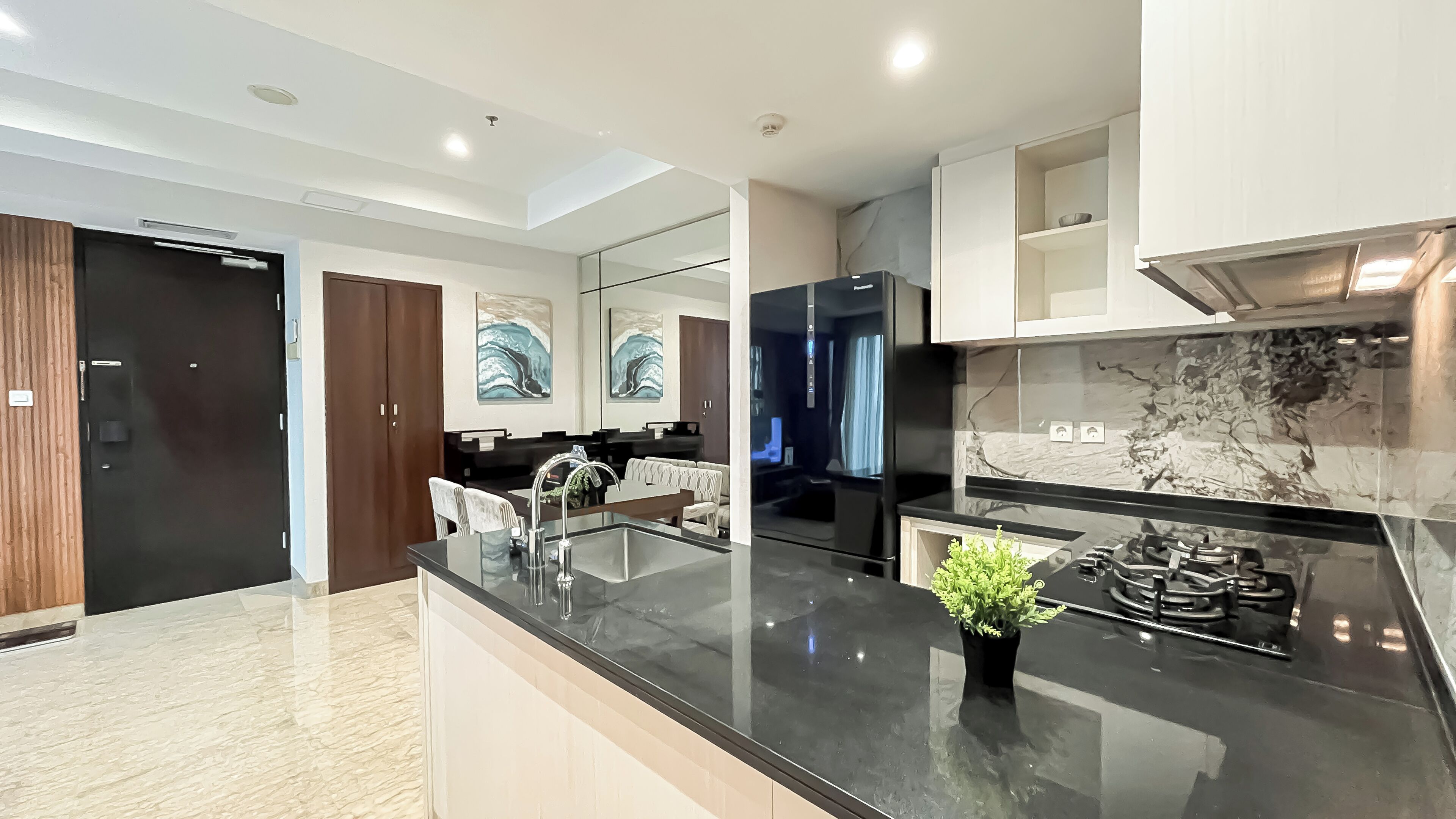 A modern kitchen with a black countertop, stainless steel appliances, and a marble backsplash.