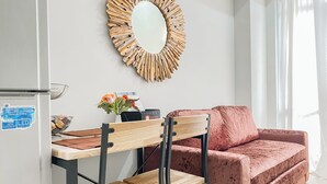 A modern living room with a red velvet sofa, a wooden coffee table, and a wall-mounted mirror. - Good Place 1Br Vasanta Innopark Apartment (Cikarang)