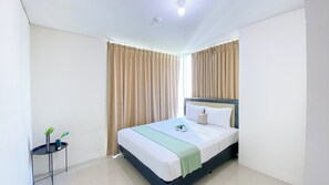 A hotel room with a bed, curtains, a small table with a plant, and a ceiling light. - Good Location And Cozy 2Br Woodland Park Residence Apartment (Jakarta)