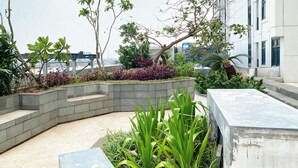 A rooftop garden with various plants and a seating area.