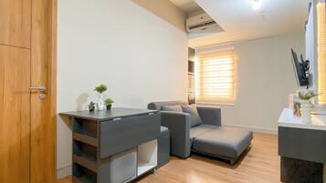Una sala de estar moderna con un sofá gris, una mesita auxiliar con un florero y una puerta de madera.