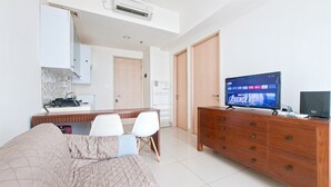 A modern hotel room with a bed, a wooden dresser, a television, and a kitchenette. - Simple Look 1Br Apartment At Tree Park City Bsd (Tangerang)