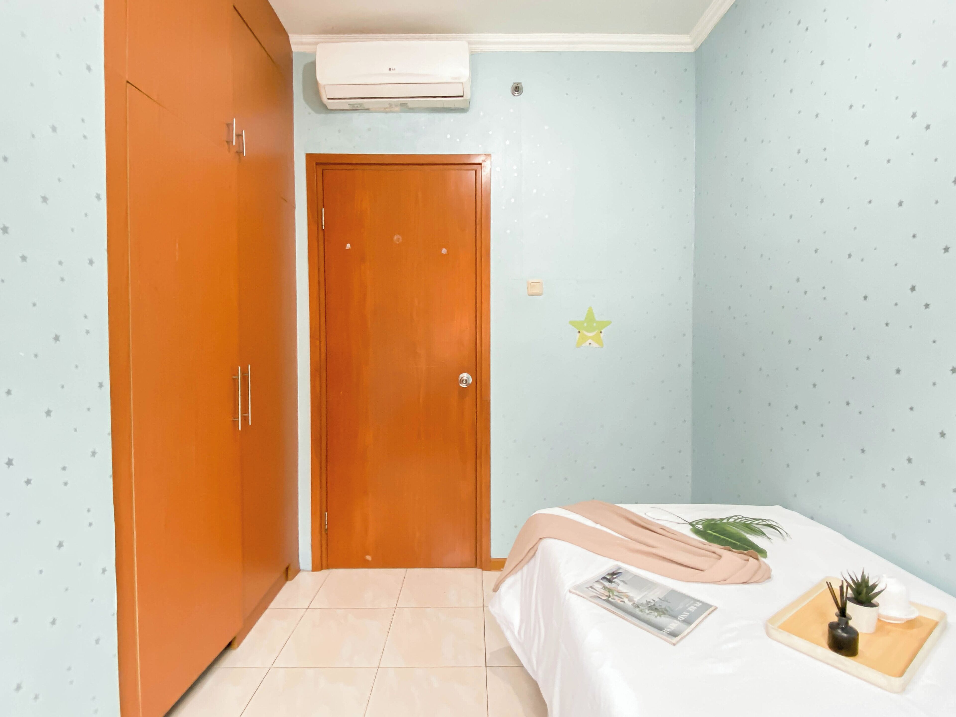Un dormitorio con cama, armario, puerta y aire acondicionado instalado en la pared.