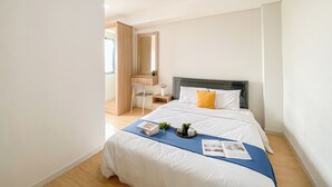 A modern bedroom with a large bed, a bedside table, a chair, and a mirror. - Scandinavian Minimalist 2Br Apartment At Daan Mogot City (Jakarta)