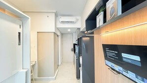 Ein moderner Flur mit integrierter Klimaanlage, einem an einer Holzwand montierten Flachbildfernseher, der eine Google TV-Oberfläche zeigt, und einer Tür zu einem weiteren Raum.