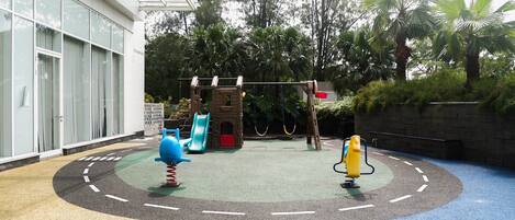 A children's play area with a slide, climbing structure, and swings.
