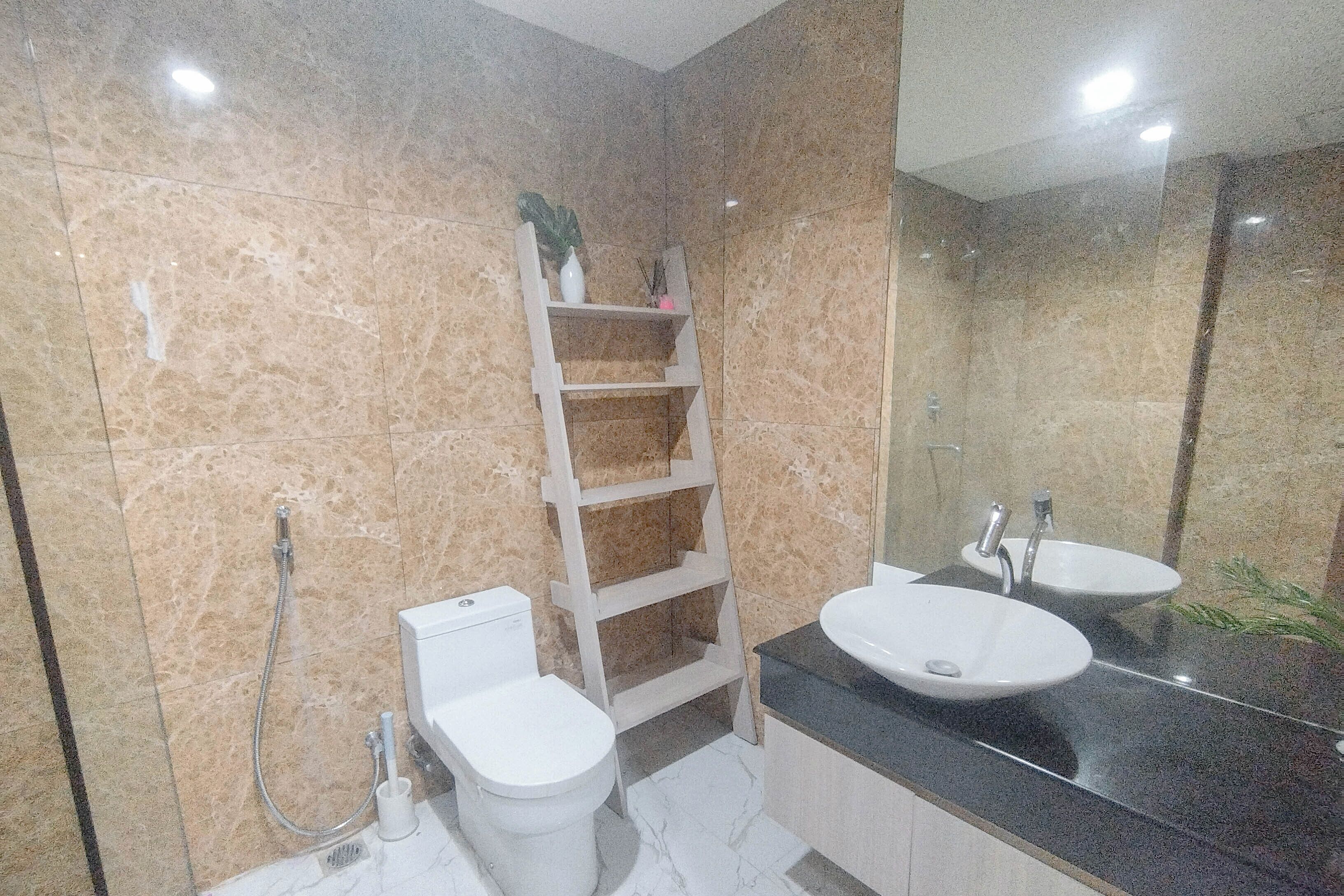A bathroom with two sinks, a toilet, a shower, a mirror, and a shelf with toiletries.